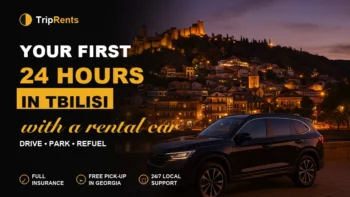 Black SUV parked on a Tbilisi embankment at dusk with Narikala fortress in the background